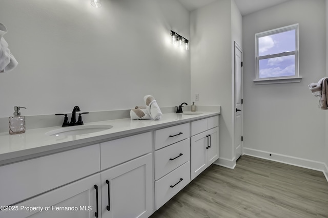 full bathroom featuring baseboards, a sink, wood finished floors, and double vanity