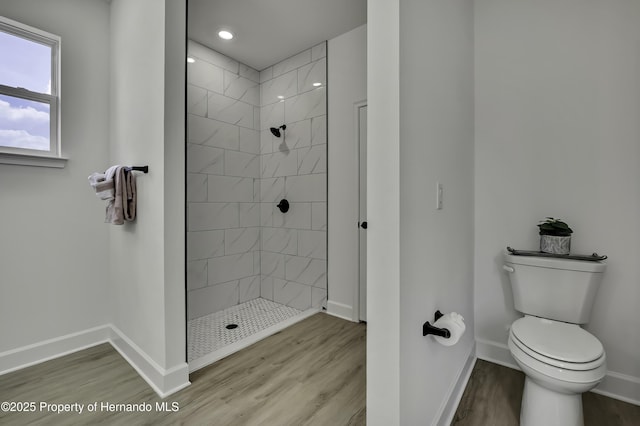 full bath featuring a tile shower, wood finished floors, baseboards, toilet, and recessed lighting