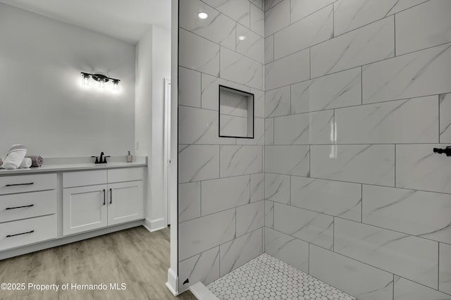 full bath with vanity, tiled shower, and wood finished floors