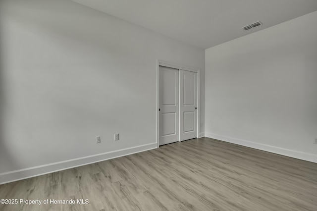 empty room with baseboards, visible vents, and wood finished floors