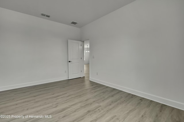 unfurnished room with baseboards, wood finished floors, and visible vents