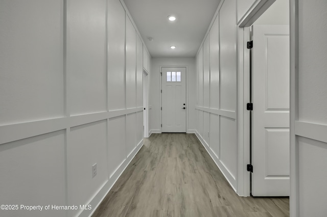 corridor featuring light wood-type flooring, recessed lighting, and baseboards