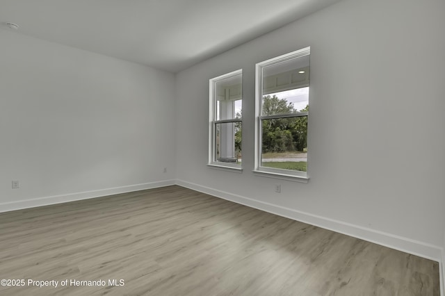 spare room with baseboards and wood finished floors