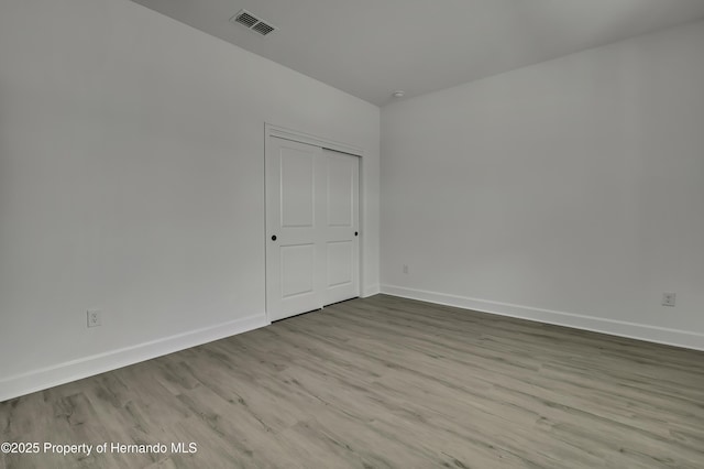 empty room featuring baseboards, visible vents, and wood finished floors