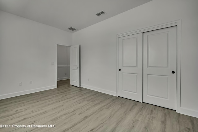unfurnished bedroom with a closet, light wood-style flooring, and visible vents