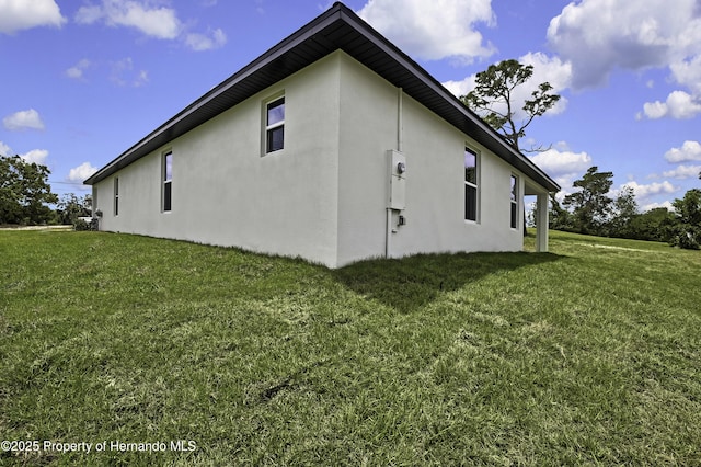 view of side of home featuring a yard and stucco siding