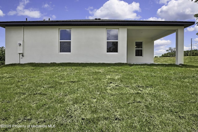 back of property featuring stucco siding and a yard