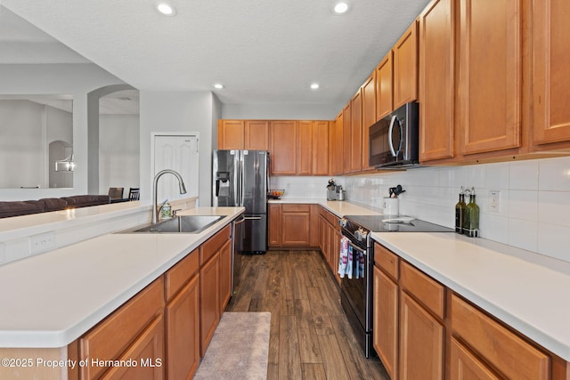 kitchen featuring stainless steel fridge, a sink, light countertops, dark wood finished floors, and black electric range