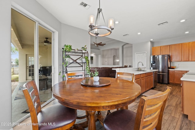 dining space with ceiling fan with notable chandelier, recessed lighting, wood finished floors, and visible vents
