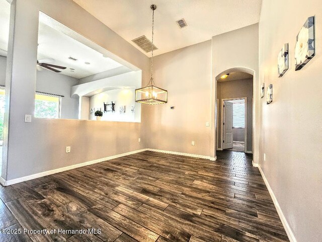 4214 Canongate Ct, Spring Hill, FL 34609 - unfurnished dining area featuring arched walkways, dark wood-style flooring, a ceiling fan, and a chandelier