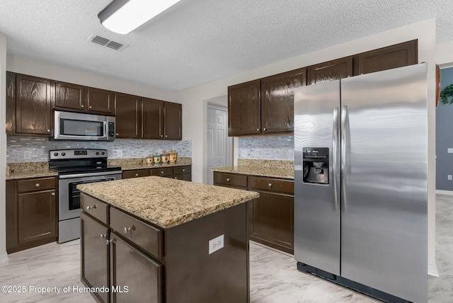 6440 Curtiss Ln, Spring Hill, FL 34608 - kitchen with stainless steel appliances, dark brown cabinets, a center island, backsplash, and a textured ceiling