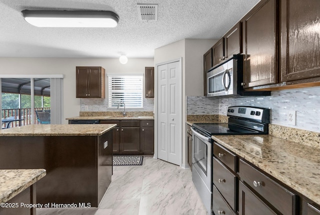 6440 Curtiss Ln, Spring Hill, FL 34608 - kitchen featuring appliances with stainless steel finishes, a sink, dark brown cabinets, light stone countertops, and light marble finish flooring