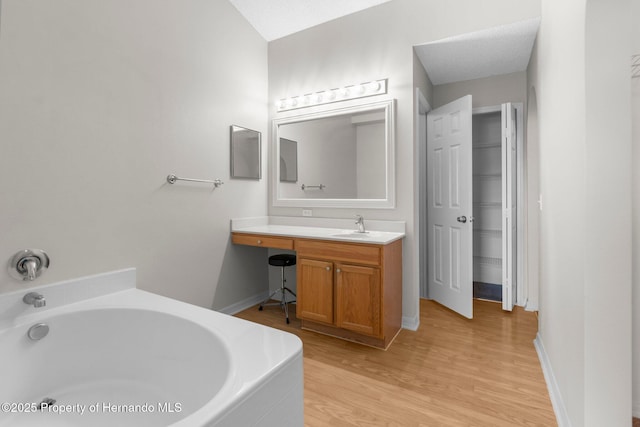 6440 Curtiss Ln, Spring Hill, FL 34608 - bathroom featuring a garden tub, wood finished floors, vanity, and baseboards