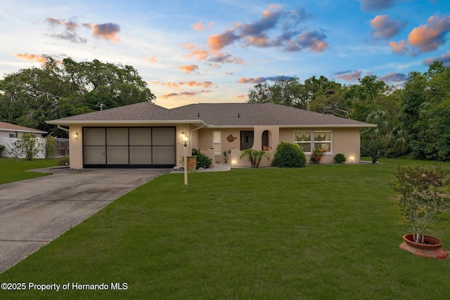 single story home featuring a yard, an attached garage, stucco siding, and driveway
