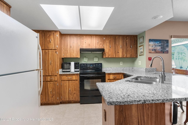kitchen featuring freestanding refrigerator, under cabinet range hood, black / electric stove, a sink, and a peninsula