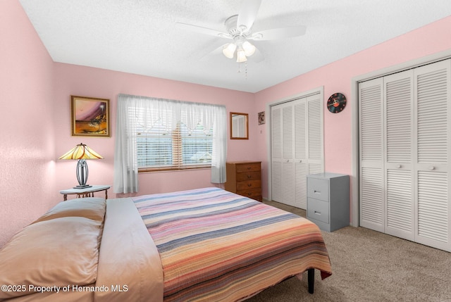 carpeted bedroom with two closets and ceiling fan