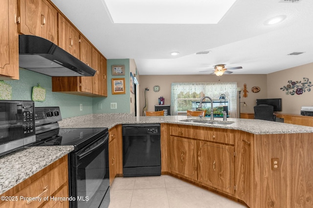 kitchen featuring a peninsula, a sink, brown cabinetry, black appliances, and under cabinet range hood