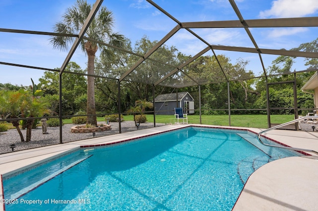 outdoor pool with a storage shed, an outbuilding, a lawn, a patio area, and a lanai