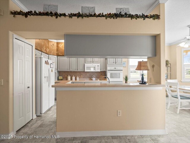 18514 Hidden Pines Way, Hudson, FL 34667 - kitchen featuring white appliances, crown molding, light countertops, decorative backsplash, and a textured ceiling