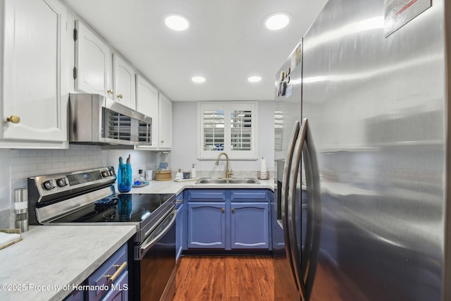 4008 Passport Ln, New Port Richey, FL 34653 - kitchen with appliances with stainless steel finishes, a sink, blue cabinetry, white cabinets, and dark wood-type flooring