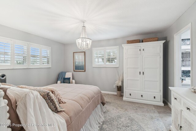 4008 Passport Ln, New Port Richey, FL 34653 - bedroom with light carpet, a chandelier, multiple windows, and baseboards