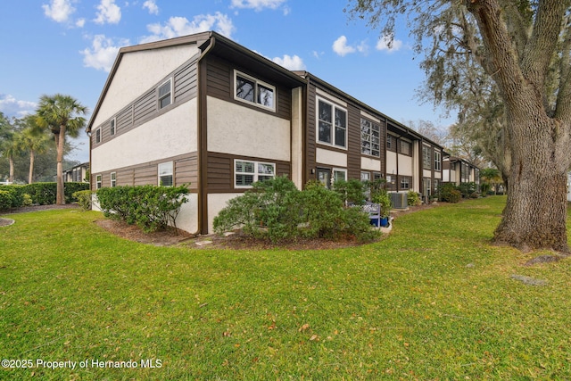 4008 Passport Ln, New Port Richey, FL 34653 - view of side of property with stucco siding, a yard, and cooling unit