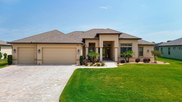 prairie-style home with stucco siding, a front lawn, decorative driveway, and an attached garage
