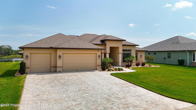prairie-style house featuring an attached garage, stucco siding, a front lawn, and driveway