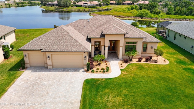 view of front of home featuring stucco siding, a garage, decorative driveway, and a water view