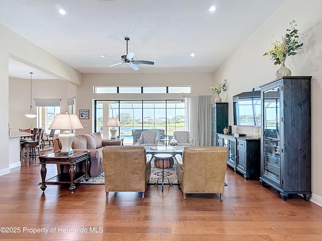 living area with wood finished floors, a ceiling fan, healthy amount of natural light, a textured ceiling, and recessed lighting