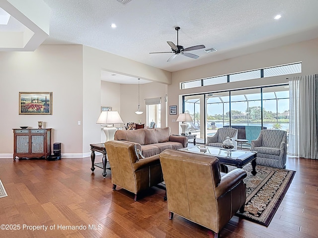 living room featuring a textured ceiling, ceiling fan, dark wood-type flooring, baseboards, and recessed lighting