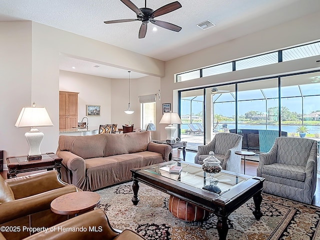 living room featuring ceiling fan, a textured ceiling, and recessed lighting