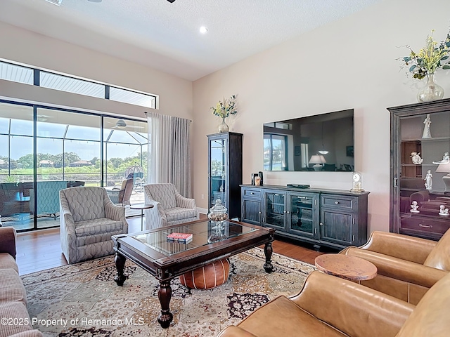 living room featuring wood finished floors, a high ceiling, and recessed lighting