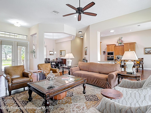 living area featuring wood finished floors, a ceiling fan, baseboards, a textured ceiling, and recessed lighting