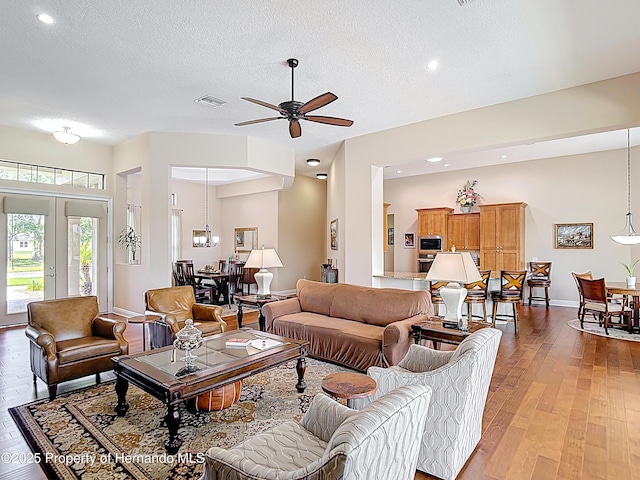 living room featuring light wood-type flooring, ceiling fan, a textured ceiling, baseboards, and recessed lighting