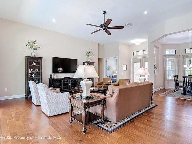 living room with wood finished floors, ceiling fan, baseboards, recessed lighting, and arched walkways