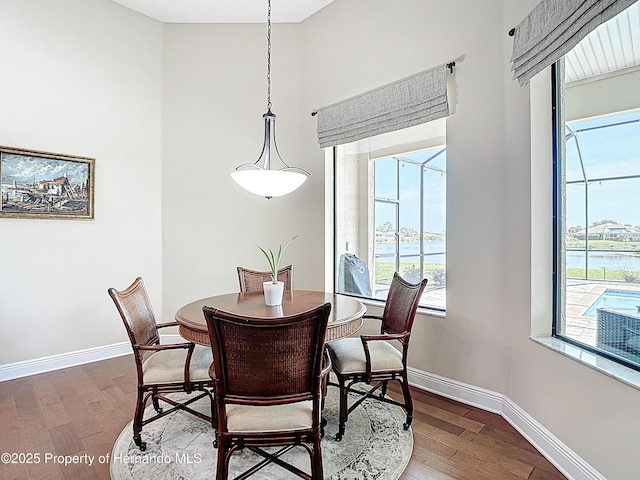 dining room with wood finished floors, baseboards, and a water view
