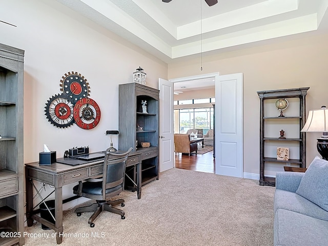 home office with carpet floors, a tray ceiling, a ceiling fan, and baseboards