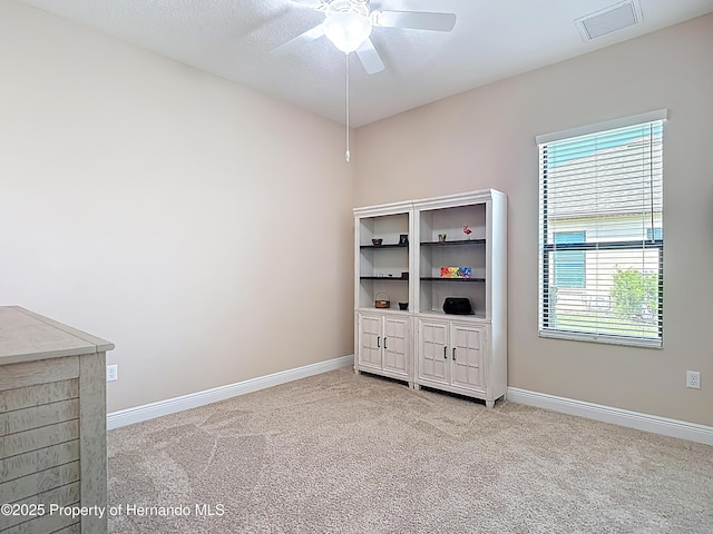 spare room with ceiling fan, light colored carpet, and baseboards