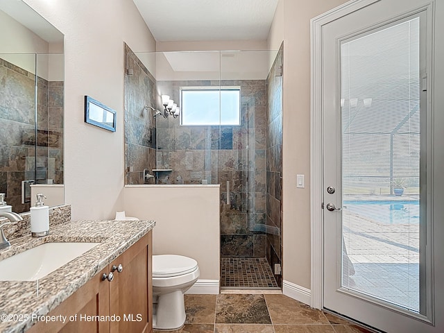 full bathroom with tiled shower, toilet, baseboards, and vanity