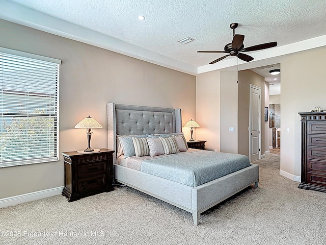 bedroom with light colored carpet, multiple windows, baseboards, and a textured ceiling