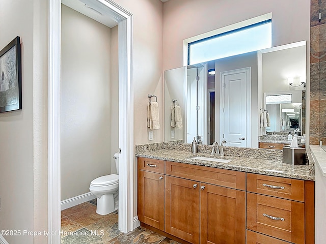 bathroom featuring toilet, vanity, and baseboards