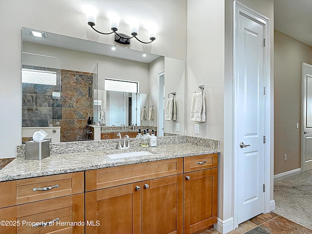 bathroom with a walk in shower, vanity, and baseboards