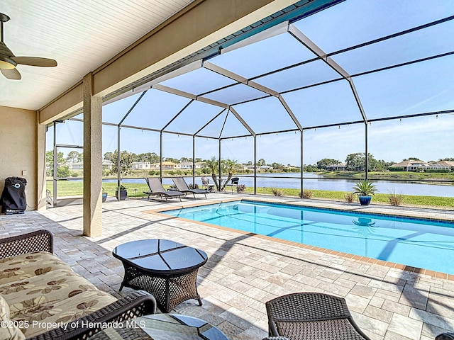 swimming pool with a patio area, ceiling fan, a water view, and a lanai