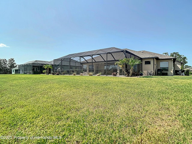 back of property with a lawn, glass enclosure, and stucco siding