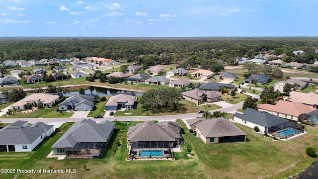 aerial view of residential area with a pool and a heavily wooded area