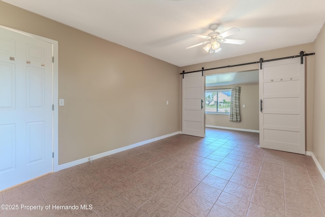 4446 San Juan Dr, Hernando Beach, FL 34607 - spare room featuring a barn door, a ceiling fan, baseboards, and light tile patterned flooring