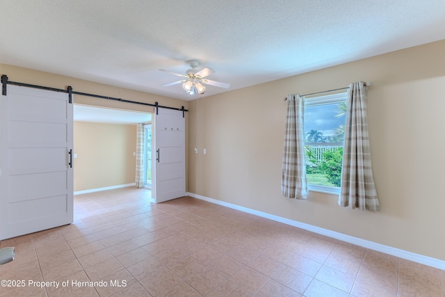 4446 San Juan Dr, Hernando Beach, FL 34607 - empty room with a barn door, a ceiling fan, baseboards, and light tile patterned floors