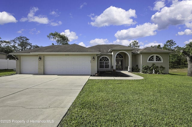 11336 Flower Ave, Weeki Wachee, FL 34613 - view of front of home featuring concrete driveway, an attached garage, stucco siding, and a front lawn