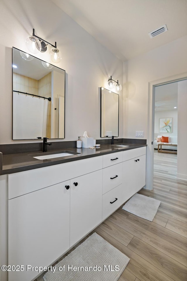 bathroom with wood finished floors and double vanity